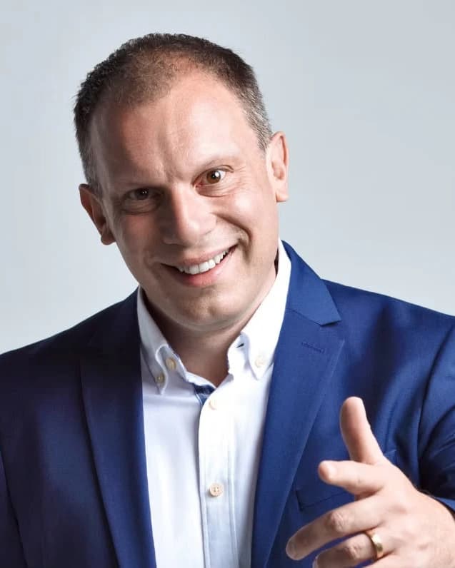 Porträt von Andreas Krättli: ein lächelnder Mann mit kurzen Haaren, blauem Sakko und weissem Hemd vor hellgrauem Hintergrund.